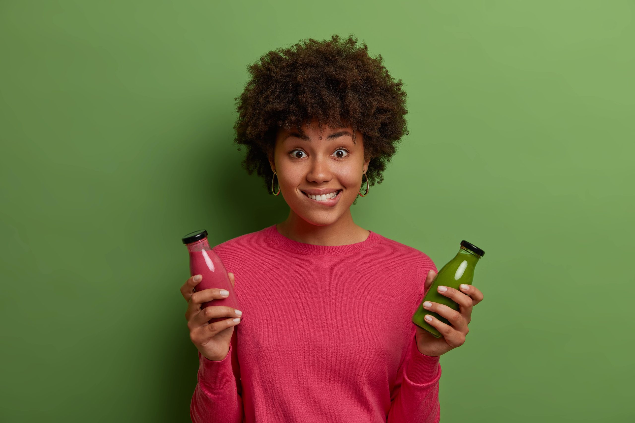Mulher segura duas embalagens de bebidas coloridas, uma em cada mão.