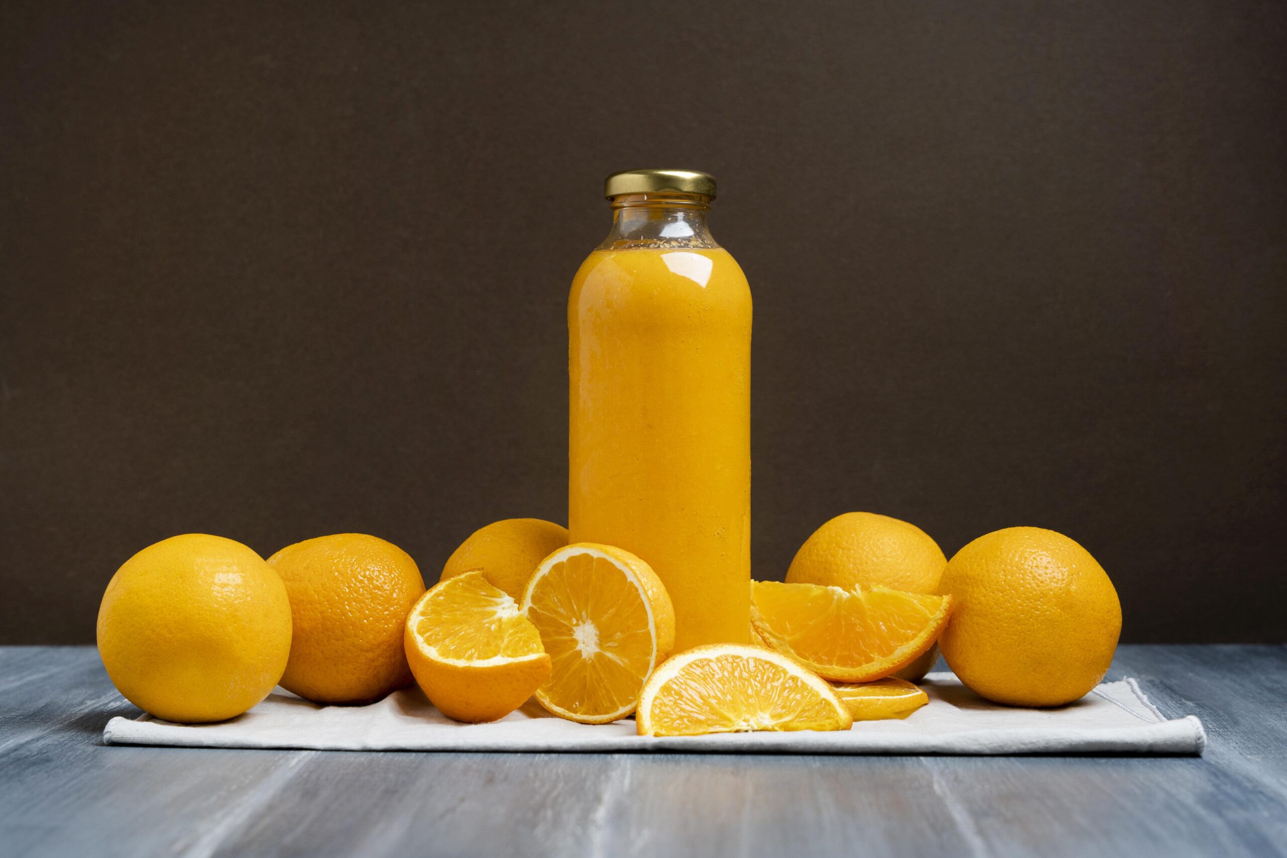 Imagem de uma garrafa de suco de laranja cercada por rodelas da fruta.